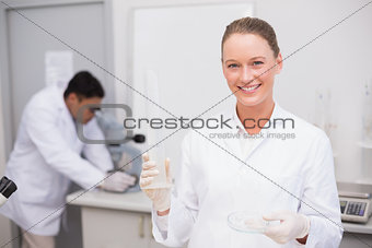 Smiling scientist filling a petri dish
