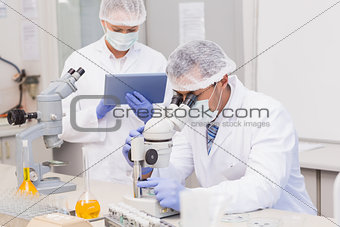 Scientists using tablet pc and microscope