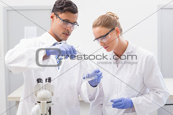 Focused scientists examining beaker