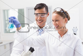 Smiling scientists looking at beaker