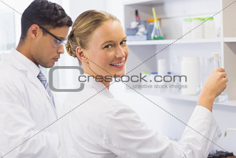 Smiling scientist looking at camera and holding a beaker