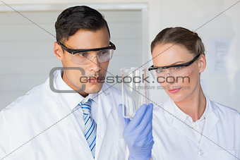 Concentrated scientists looking at beaker