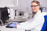 Smiling scientist looking at camera and using computer