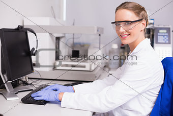 Smiling scientist looking at camera and using computer