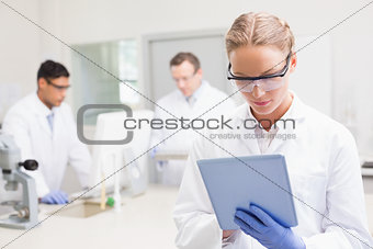Scientist using tablet while colleagues working behind