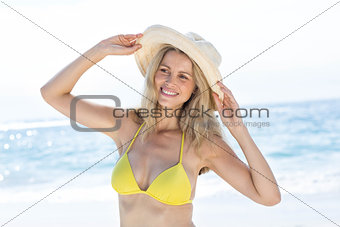 Smiling pretty blonde in bikini wearing straw hat