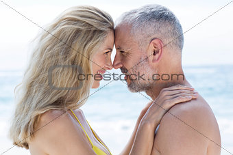 Happy couple standing by the sea and smiling at each other
