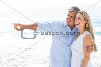Happy couple standing by the sea and pointing something
