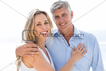 Happy couple standing by the sea and smiling at camera
