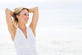 Smiling blonde in white dress standing by the sea