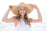 Smiling blonde in white dress looking at camera and wearing straw hat