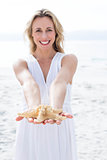 Smiling blonde in white dress holding starfish