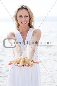 Smiling blonde in white dress holding starfish