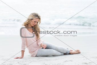 Smiling pretty blonde relaxing on the sand