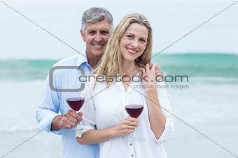 Happy couple smiling at camera and holding a glass of red wine
