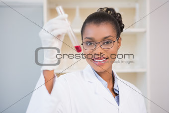 Smiling scientist showing test tube with red fluid