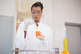 Concentrated scientist examining orange fluid