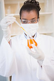 Concentrated scientist examining orange fluid with pipette