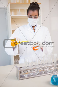 Concentrated scientist pouring orange fluid
