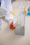 Scientist pouring orange fluid in test tube