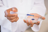Scientist examining blue fluid in petri dish