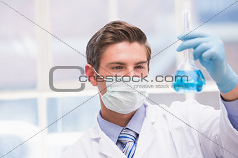 Scientist examining beaker with blue fluid