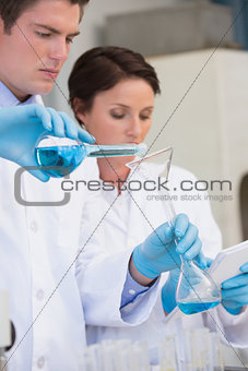 Scientists pouring chemical fluid in funnel