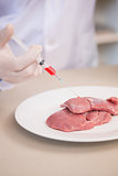 Scientist doing injection to pieces of meat