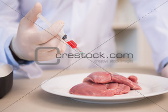 Scientist doing injection to pieces of meat
