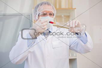 Scientist injecting red liquid in flask