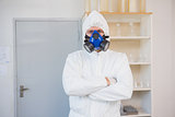 Scientist in protective suit looking at camera with arms crossed
