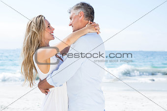 Happy couple smiling at each other by the sea