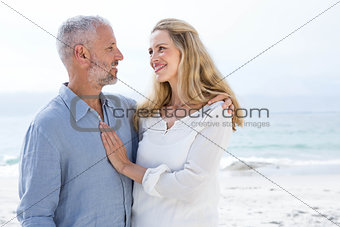 Happy couple smiling at each other by the sea