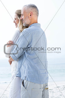 Happy couple hugging each other and looking at the sea