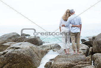 Happy couple standing on the rock and looking at the sea