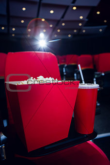 Empty rows of red seats with pop corn and drink