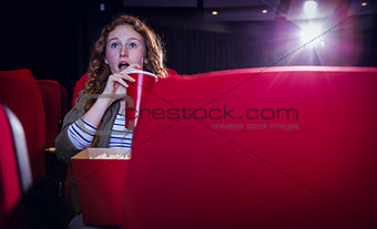 Young woman watching a film and drinking a soda