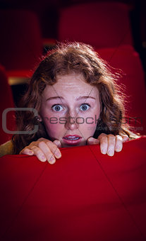 Young woman watching a scary film