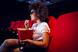 Young woman watching a 3d film and eating pop corn