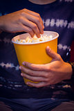 Young man watching a film and eating pop corn