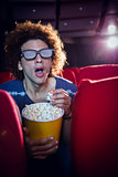 Young man watching a 3d film and eating popcorn