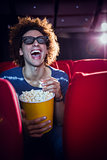 Young man watching a 3d film and eating popcorn