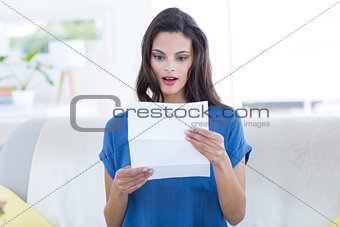 Surprised beautiful brunette reading letter