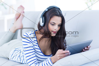Smiling beautiful brunette listening music while using her tablet