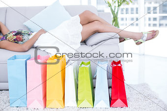 Brunette lying on the couch with shopping bags around her