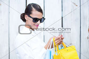 Pretty woman using her smartphone holding shopping bags