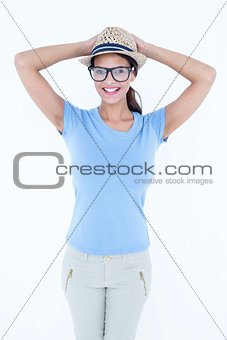 Happy brunette woman with hands on her hat