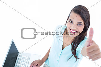 Pretty woman using her laptop with thumb up