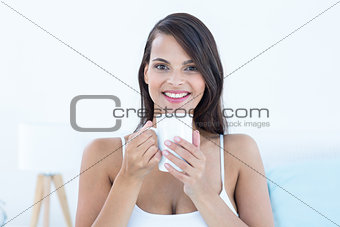 Pretty woman looking at camera holding cup of coffee