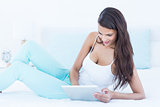 Beautiful woman using tablet pc on her bed